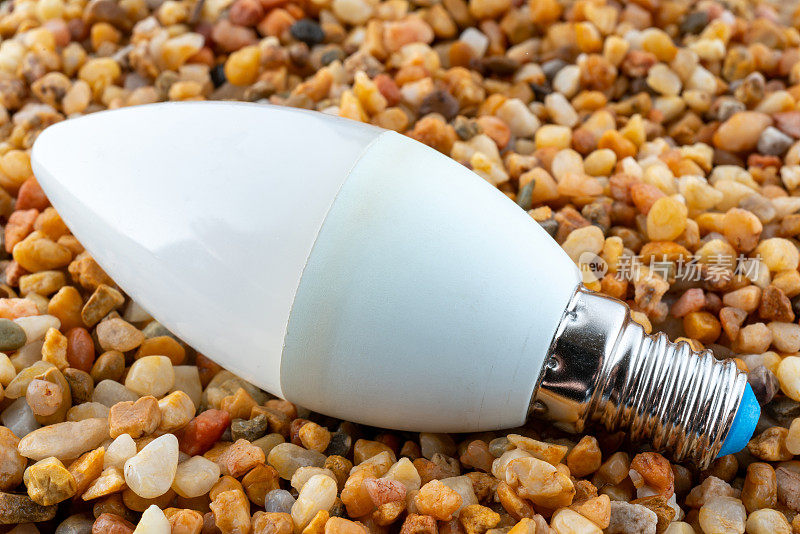 LED灯泡躺在沙滩上。
