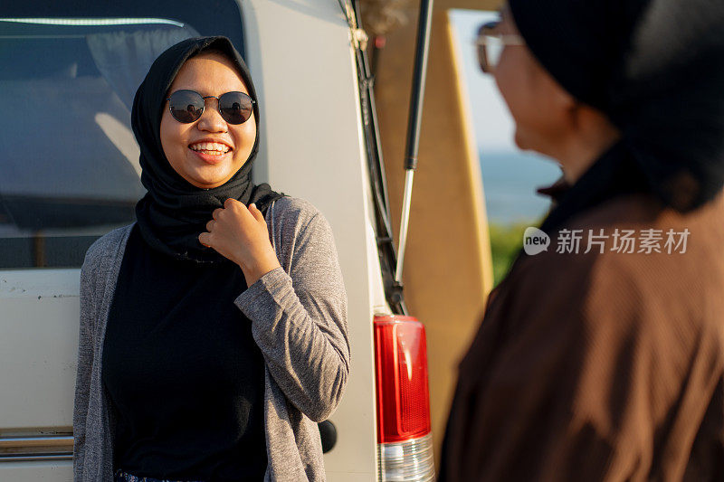 日落时分，两名穆斯林妇女在一辆露营车附近聊天