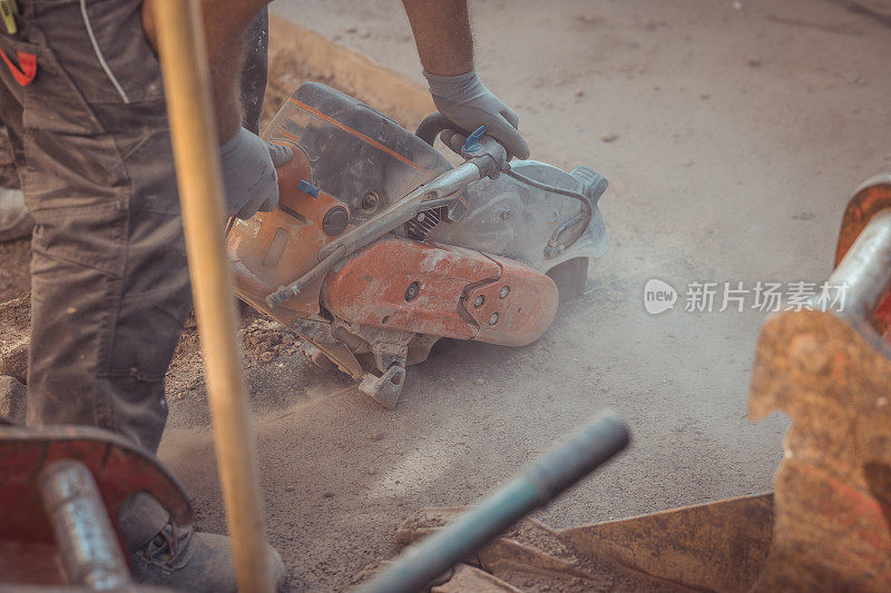 沥青切割工人使用带圆形刀片的电动沥青切割机或锯切割沥青地面，作为修复或解决问题的过程。
