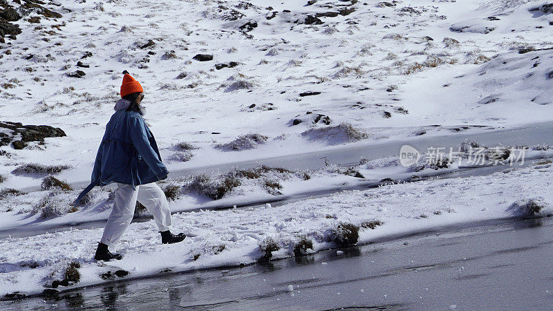 一个女人在寒冷的天气里穿行于白雪覆盖的山林之中