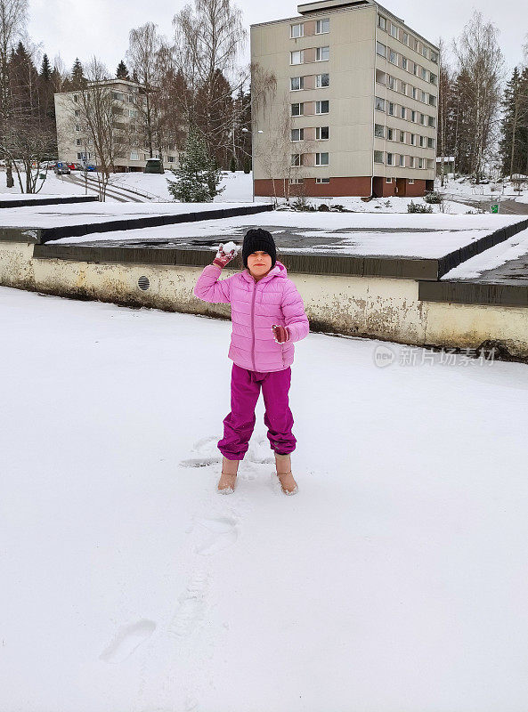 一个8岁的白种女孩在扔雪球的时候笑了。