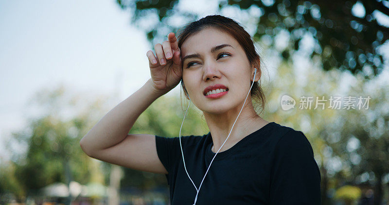 疲惫的年轻女子在运动后擦去脸上的汗水。