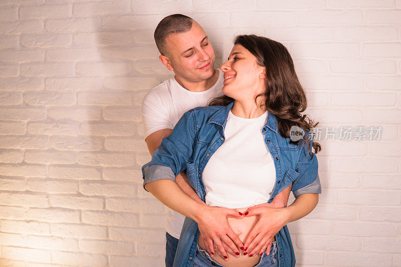 年轻的孕妇和丈夫在她的肚子上做了一个心形