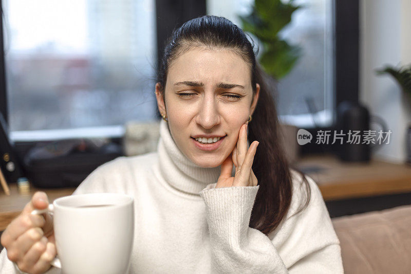 不幸的女孩强烈牙痛，触摸脸颊，喝热茶后感到牙痛