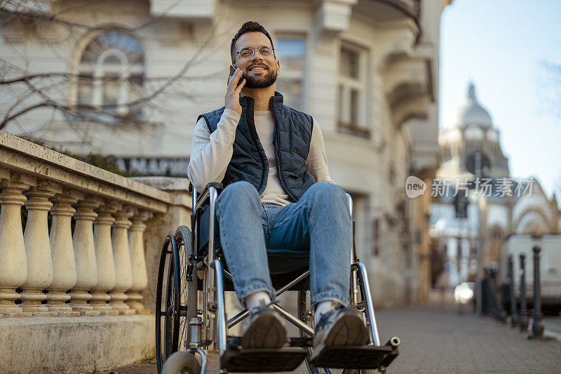 轮椅上快乐的残疾男性在户外使用智能手机