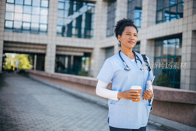 穿着制服的年轻护士在诊所前喝咖啡休息