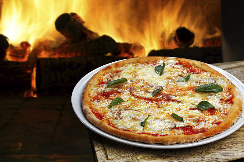 桌子上放着披萨，背景是火