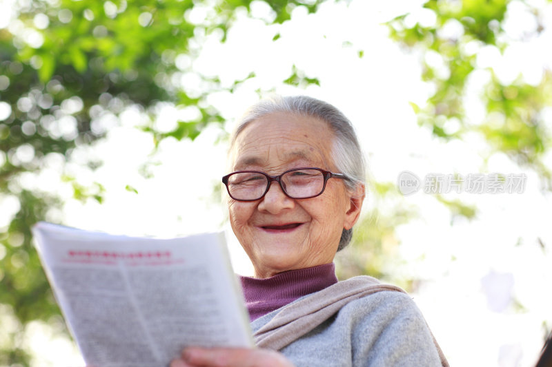 快乐的老妇人在院子里看杂志