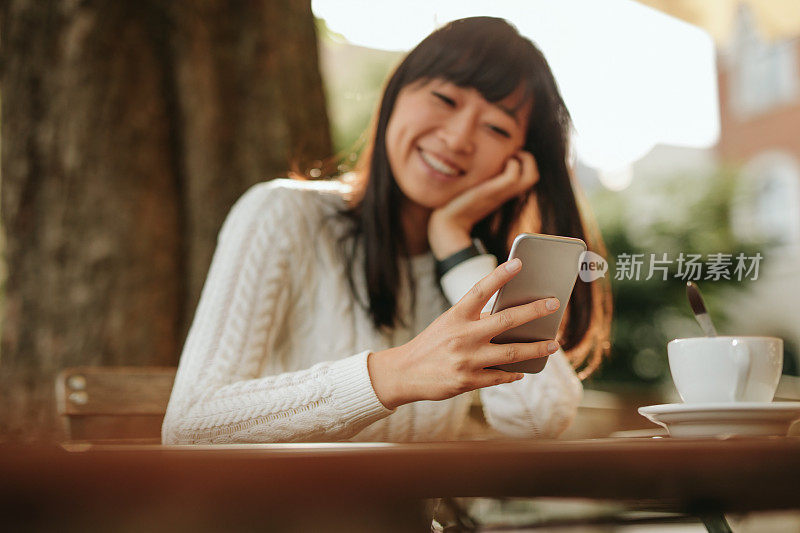 微笑的女人在咖啡馆使用智能手机