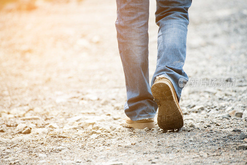 孤独的男人穿着牛仔裤和皮靴走路