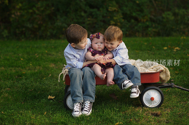 两个兄弟抱着妹妹坐在马车上