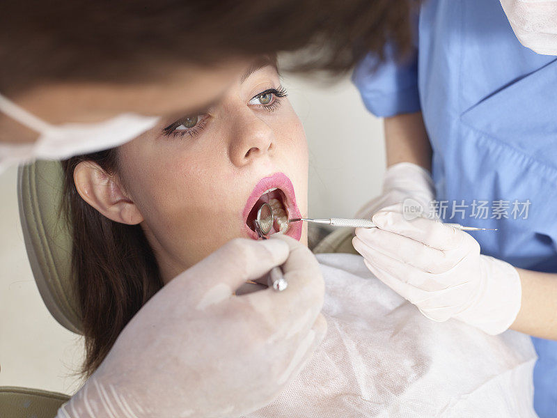 牙医兼助理检查女孩的牙齿