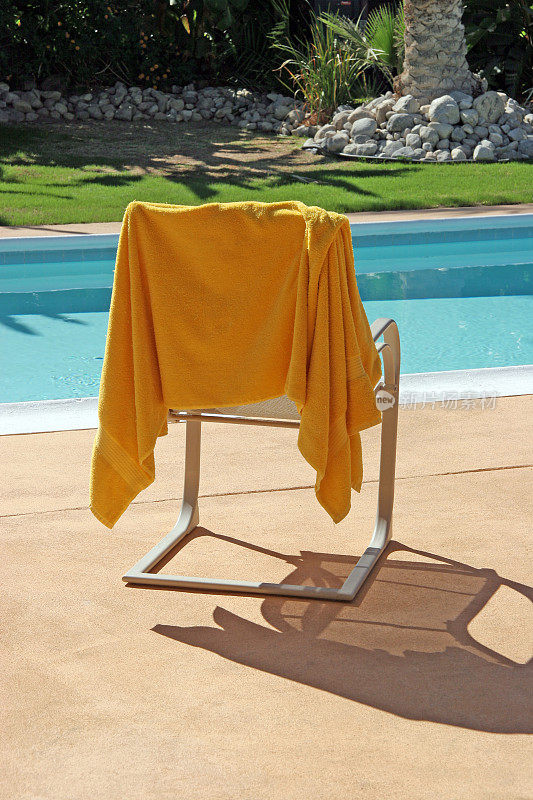 悬挂在泳池边的黄色毛巾