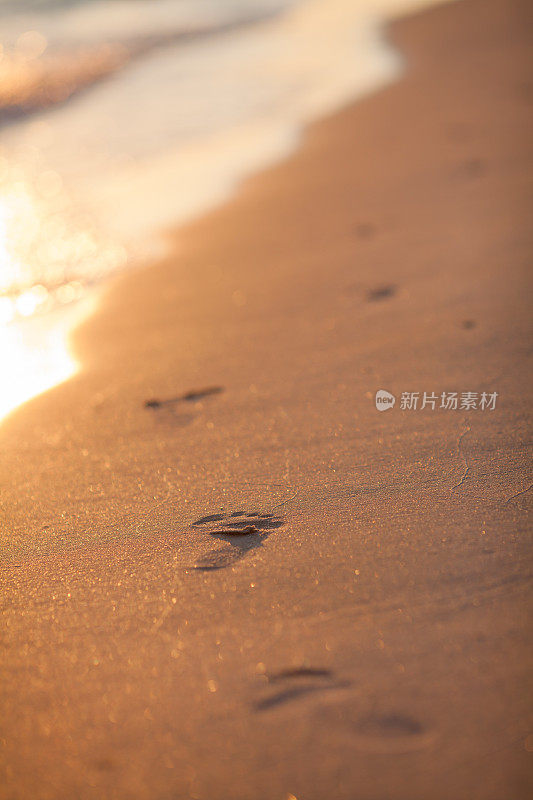 日落时分的海滩，海浪和脚印