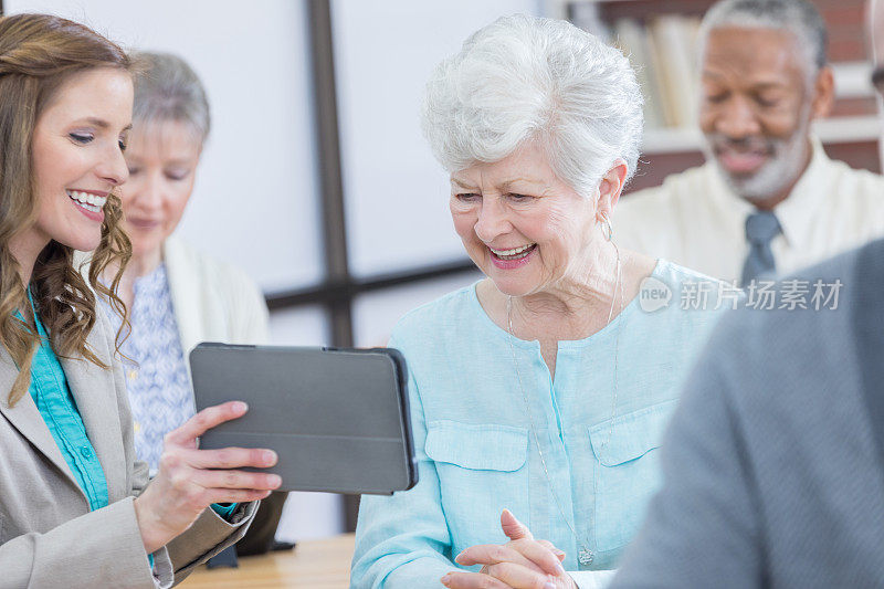 中年妇女教老年妇女使用数字平板电脑