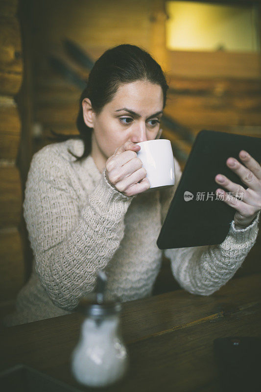 坐在咖啡馆里用平板电脑工作的女人