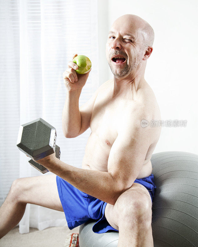 一位老人一边举重一边吃青苹果。