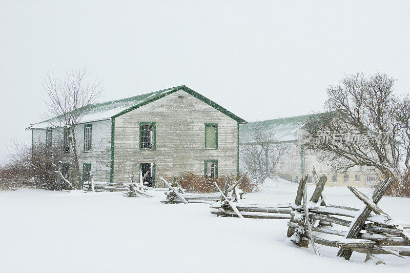 谷仓和农场在冬季大雪与栏杆栅栏
