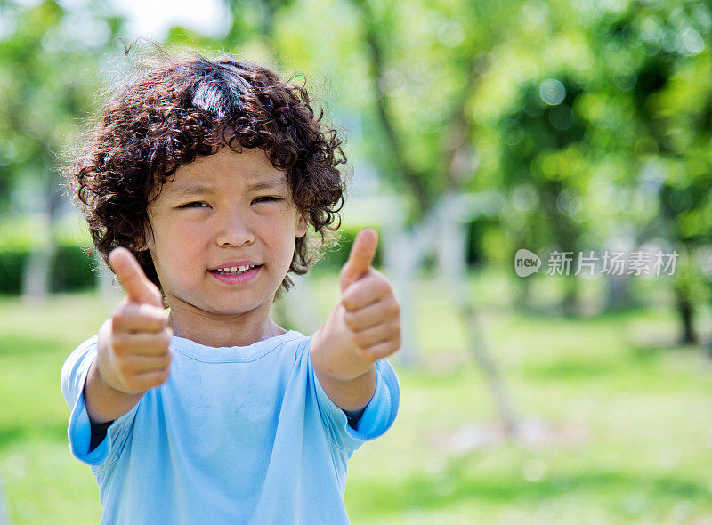 快乐的小男孩在户外竖起大拇指