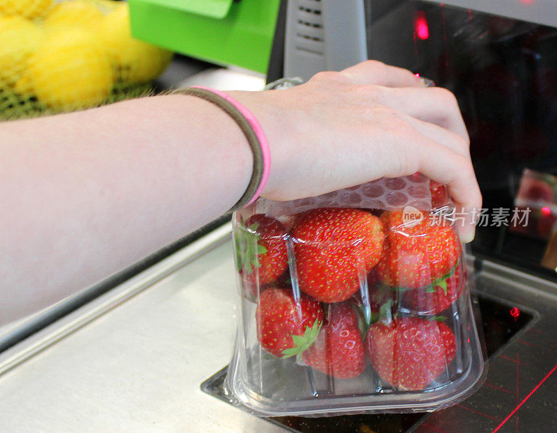 超市自助结账机，顾客用条码扫描草莓