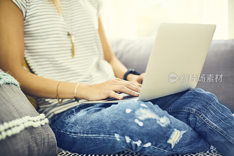 年轻女子的腹部在靠窗的座位上使用笔记本电脑