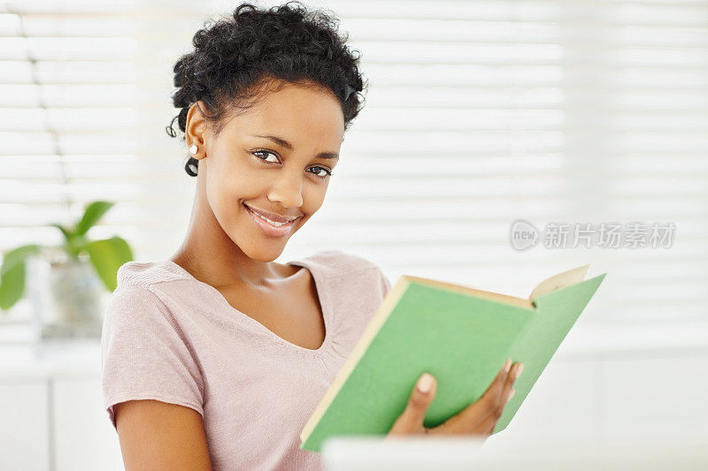 微笑的非洲裔美国年轻女士拿着一本书