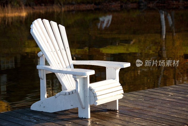 水上木制码头上的空白色阿迪朗达克椅子。