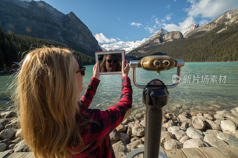 游客使用数字平板摄影露易丝湖景观
