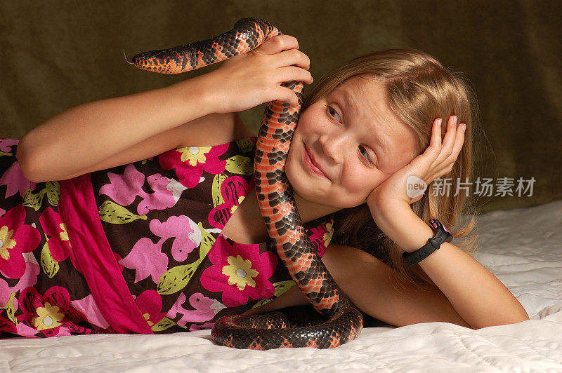 年轻女孩注视着一条彩色的蛇。