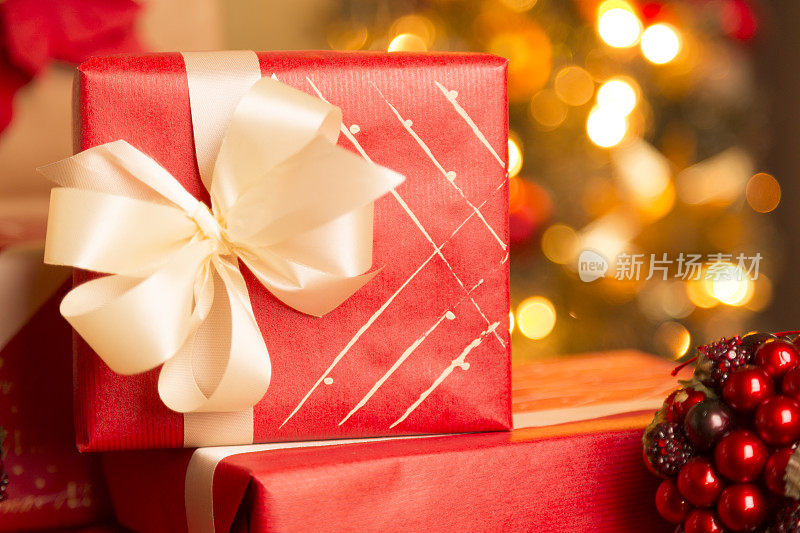 圣诞节:包装精美的节日礼物放在圣诞树前。