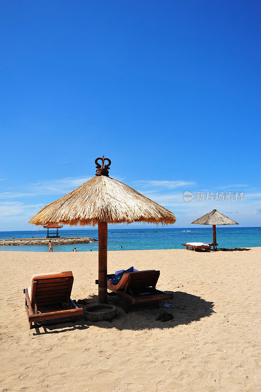 面向大海的沙滩椅和草伞