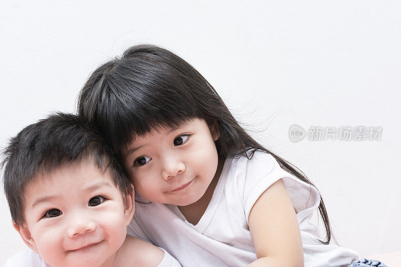 小妹妹和穿着白衬衫的弟弟互相拥抱着。