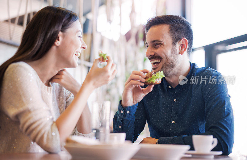 一对年轻漂亮的夫妇坐在咖啡馆里吃早餐。爱,食物,生活方式