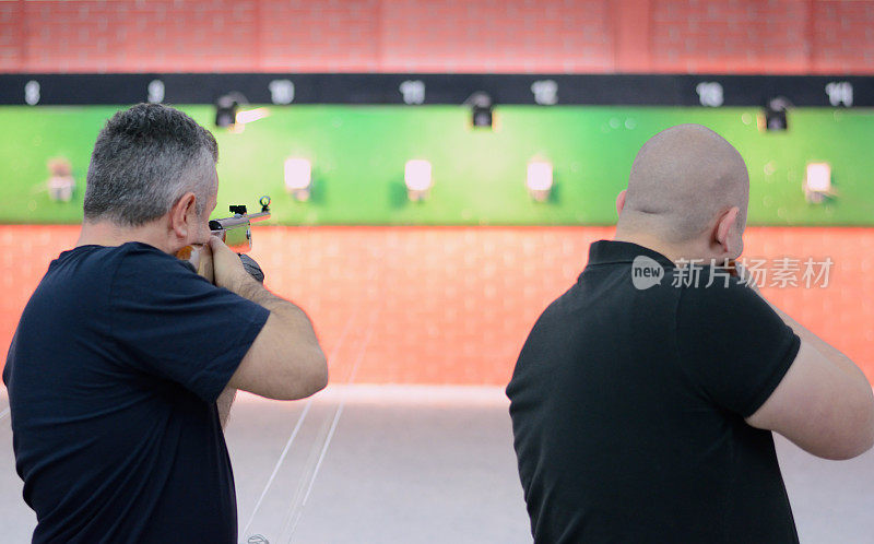 两名男子用气步枪瞄准比赛。