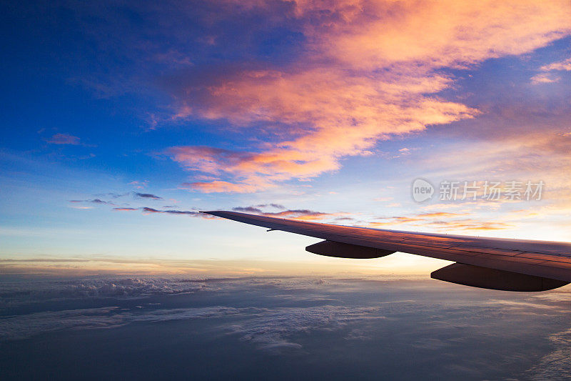从窗口飞行的飞机机翼，日落的天空