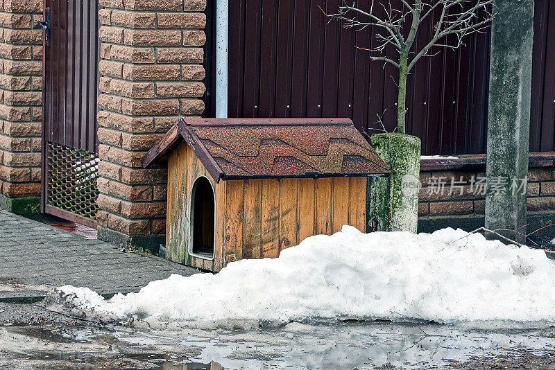 雪堆中篱笆附近的一个空狗棚