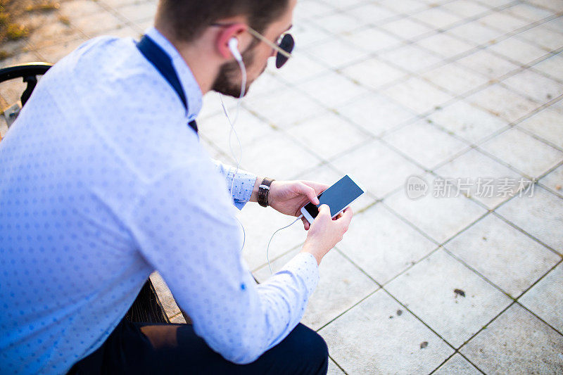 坐在长椅上的男人正在用智能手机