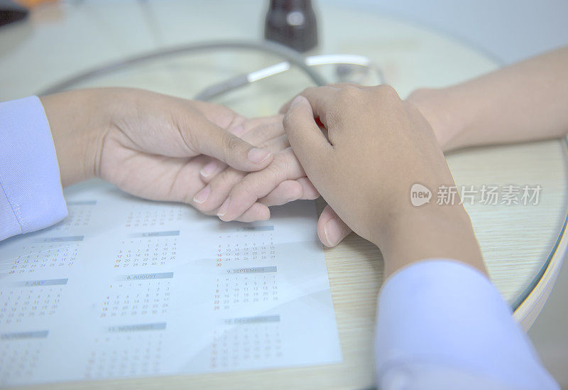 柔焦，医生握着病人的手，以寻求安慰。并确保治疗计划。