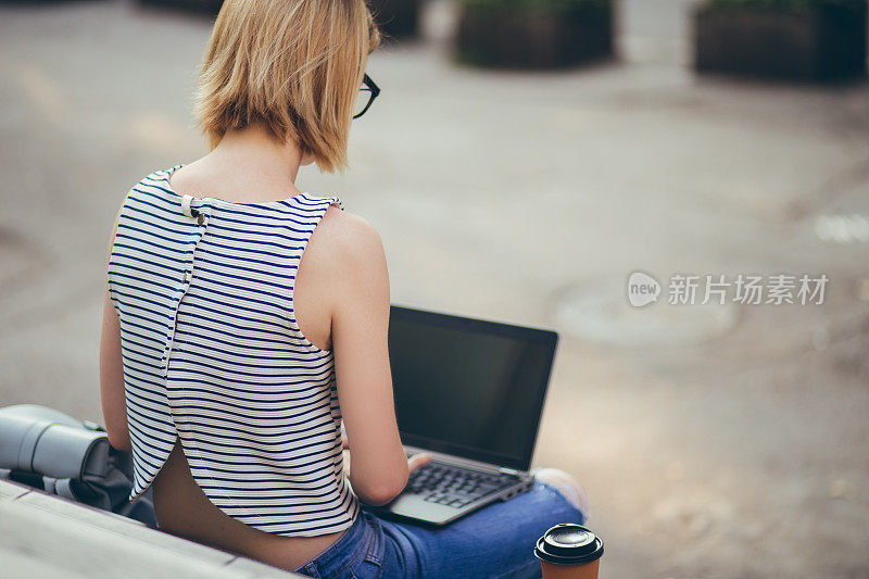 一个女学生在楼梯上用笔记本电脑学习