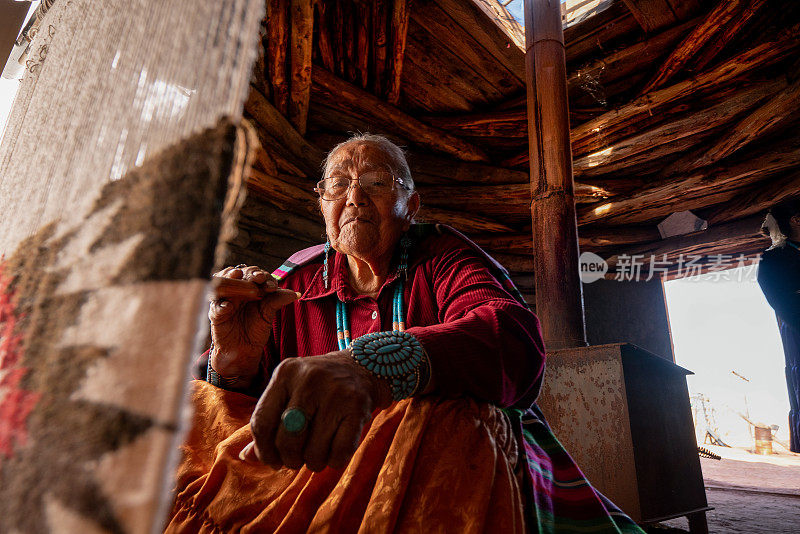 年迈的印第安纳瓦霍妇女正在霍根织布机上编织传统的部落毛毯