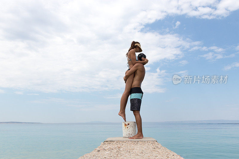 男人把女人举到海边的空中