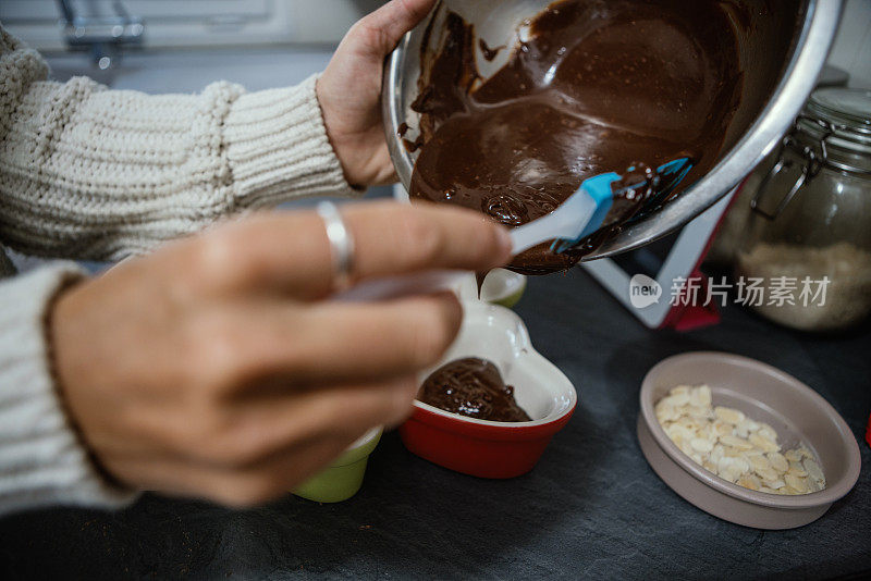 近距离的女人的手烤巧克力蛋糕浇准备心蛋糕模具，自制食物的概念