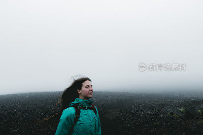 女人背包徒步旅行，虽然火山景观和风在冰岛无处