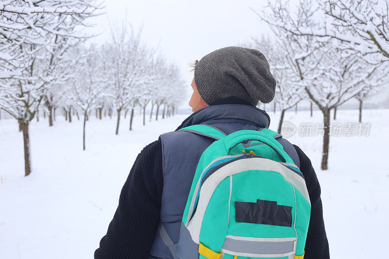 成年男子徒步旅行者戴着针织帽徒步在下雪的冬天的自然