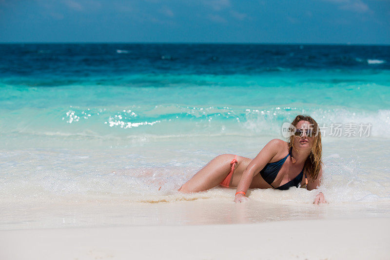 年轻女子放松在一个田园诗般的白色沙滩热带海滩