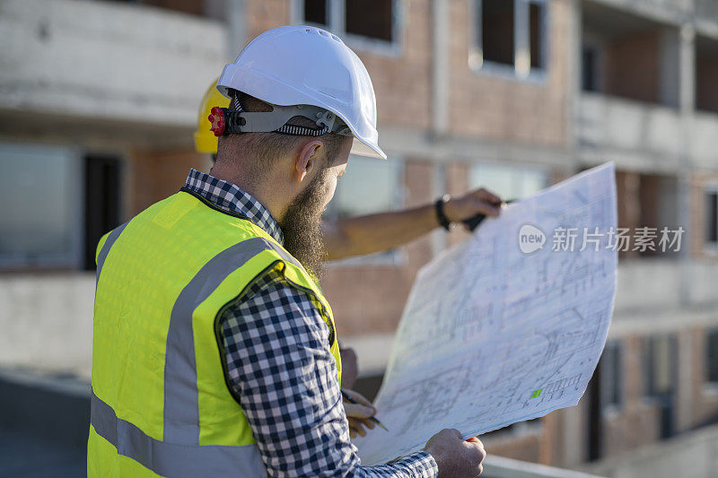 建筑师在工地上审阅设计图。