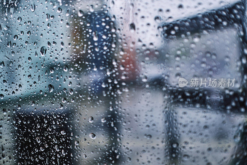 散焦的城市透过玻璃与雨滴。