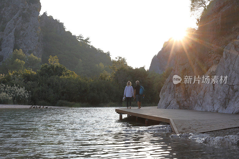 日出时分，一对夫妇沿着湖滨码头散步