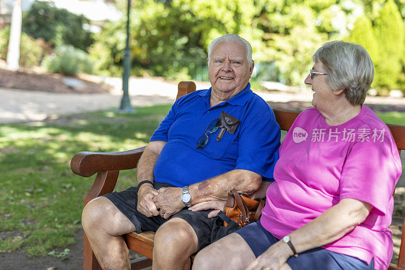 一对老年夫妇坐在公园长椅上聊天