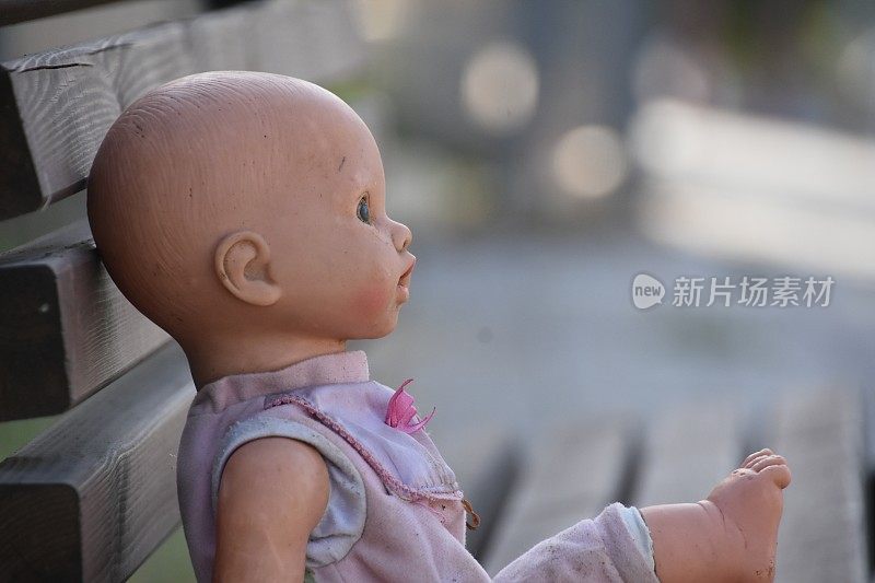 一个洋娃娃坐在公共长椅上